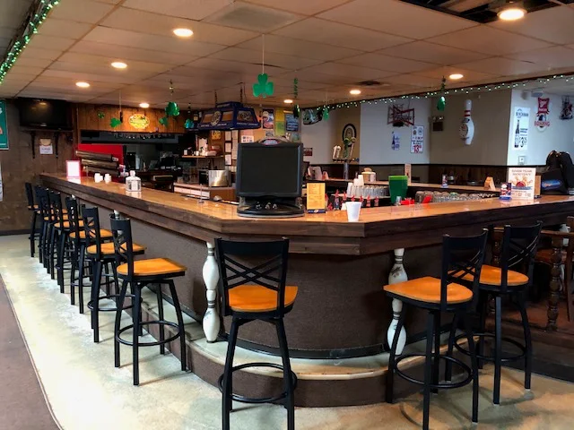 Full-service bar with wooden counter and stools